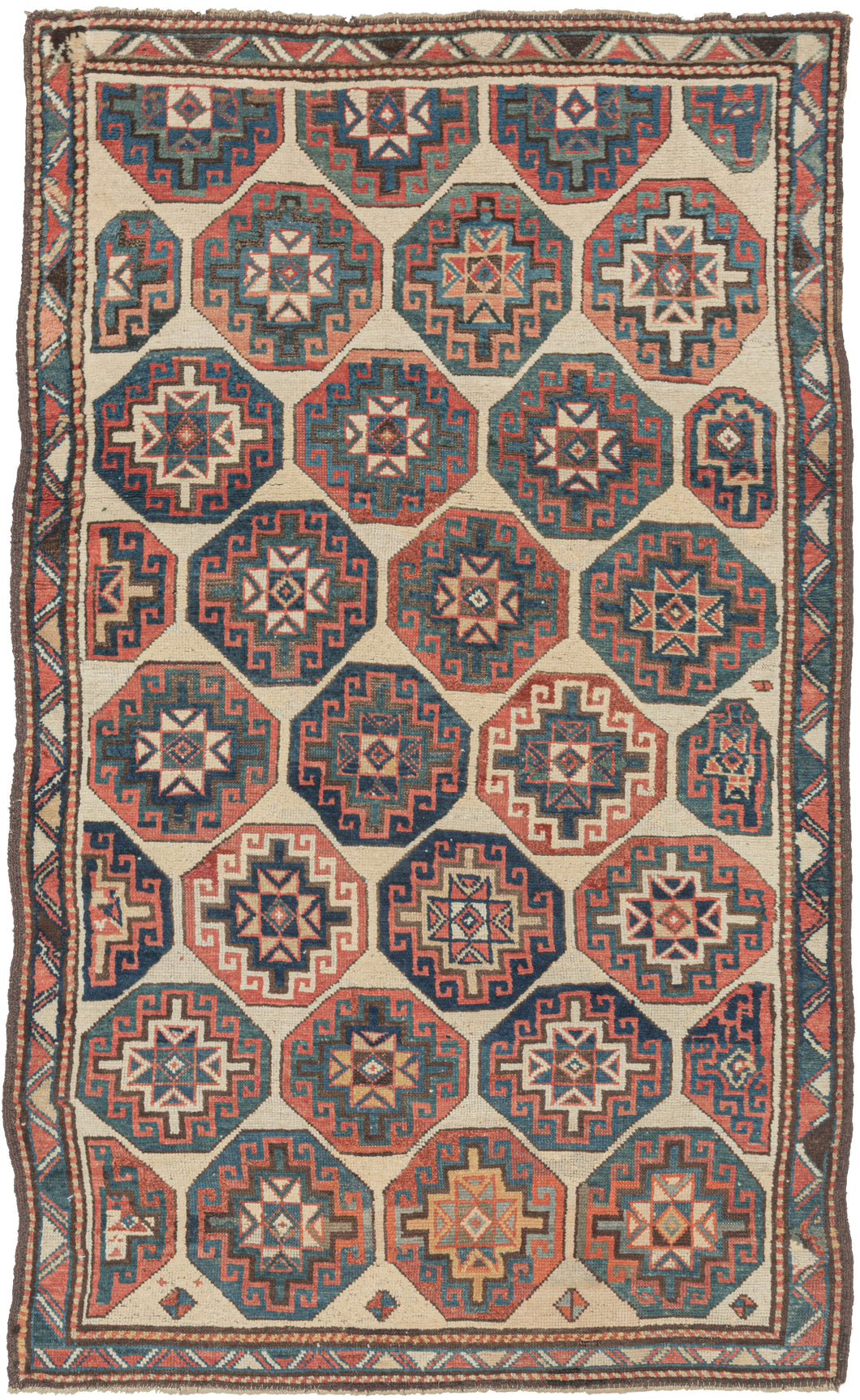 Antique Caucasian Kazak rug featuring offset Memling guls in primary colors of red, blue, and yellow on a soothing ivory ground and framed by an interlocking sawtooth border. Some guls become distorted as these reach the edges. Gentle abrash, wonderful spacing, a pleasing palette, and just enough wonkiness make this a very satisfying piece. 