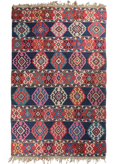 Antique Caucasian Shirvan kilim featuring a horizontally striped design, with each stripe containing geometric shapes and symbols. The color palette contains madder reds, indigo blues, deep browns, and light creams. 