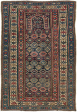 Antique Chichi prayer rug featuring classic chi-chi patterning of staggered rows of hooked polygons in soft blues, yellows, greens, and reds on a deep navy field. The top of the field is crowned with a horseshoe-shaped mihrab denoting it was likely intended as a prayer rug. Small symbols can be seen surrounding the mihrab including small combs and blossoming flowers.