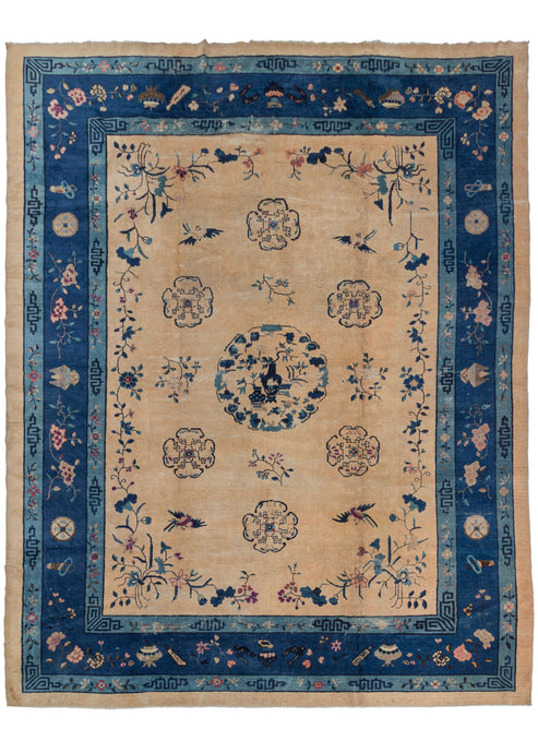 Antique Chinese Fa-Ti roomsize rug featuring a simple central medallion depicted plant filled vases. There are pictorial scenes of birds and flowers lightly drawn in blue on a tan ground. A large indigo main border and showcases flowering lotuses and coins among other auspicious symbols representing the “eight precious things”.
