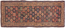 Antique Kurdish Veramin runner featuring an allover field of vibrant hooked devices in a wide array of tones including red, pink, blue, green brown, and yellow which really pop against the deep surmah or blue/black ground. The field composition plays well with the camel ground scrolling lattice main border. An additional distinction is added with the minor borders with a scrolling rosette inner border and bold laleh abbasi outer border. 