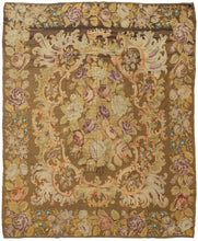 Antique Moldovan Kilim featuring a central bouquet of plush cabbage roses in soft purples, delicate oranges and ivory framed by orange baroque "c" scrolls  ands giant acanthus leaves with touches of sage and lilac. The whole is framed by a wide border of bountiful blossoms of various types with lively curling leaves. The whole is on a chocolate ground and has a sepia haze which blunts the colors beneath and gives it a golden glow.
