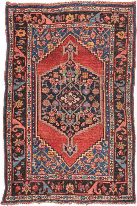 antique Persian Bidjar scatter rug featuring a midnight blue central medallion floating atop an open and undulating red lacquer field. A variation of the herati design can be found in both the medallion and the cornices which are rendered in blues, greens, pinks, and yellow. Upon closer inspection, various abstracted animals can be found in the pattern. 