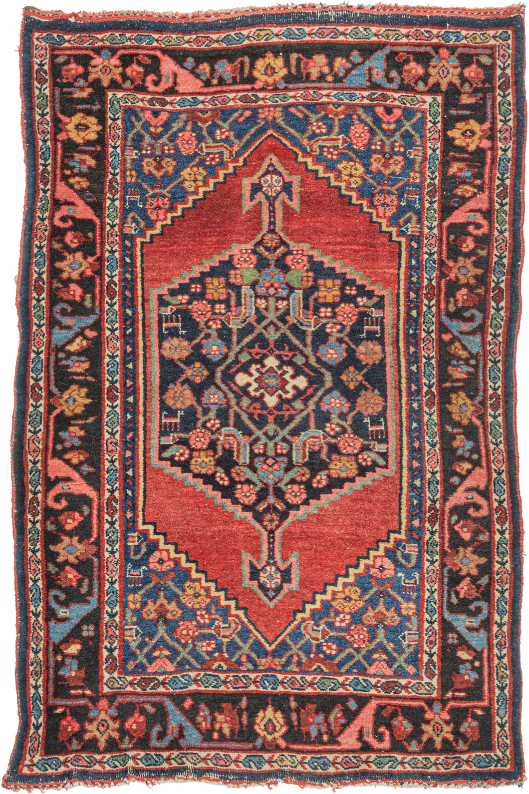 antique Persian Bidjar scatter rug featuring a midnight blue central medallion floating atop an open and undulating red lacquer field. A variation of the herati design can be found in both the medallion and the cornices which are rendered in blues, greens, pinks, and yellow. Upon closer inspection, various abstracted animals can be found in the pattern. 