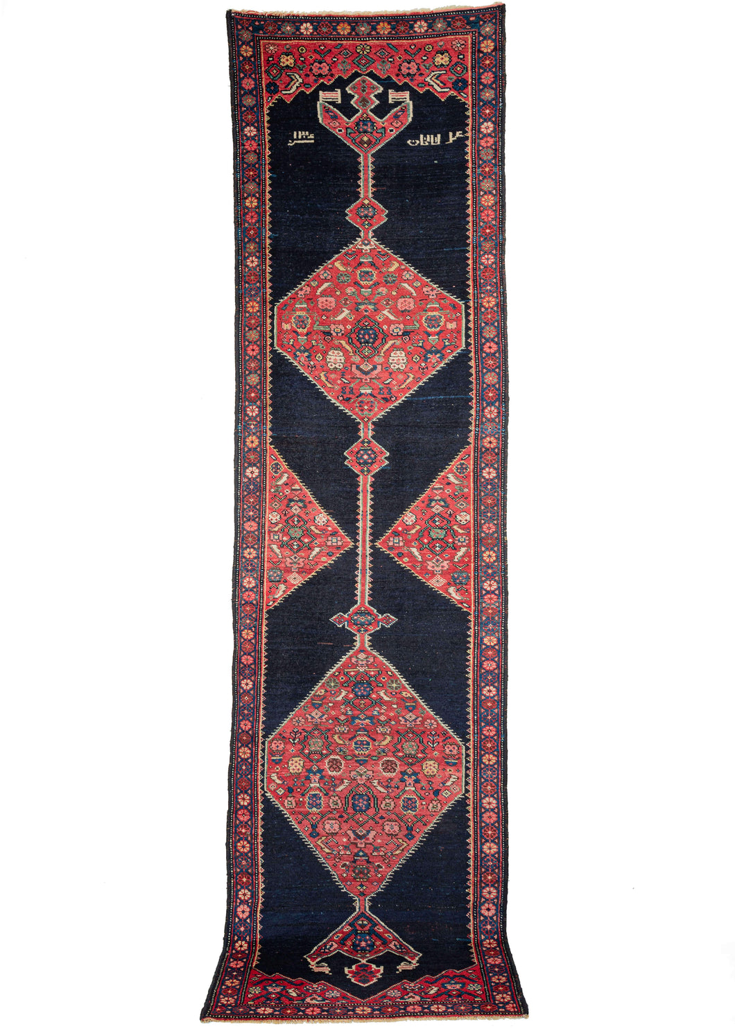 Anntique NW Persian Kurdish runner featuring composed of two red grounded lozenges filled with a variation on the classic Herati pattern. This is contrasted by the simple yet very deep navy field. There is a date (1306) and the word 