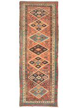 This Antique NW Persian Runner features large diamonds in orange, brown, light, and dark blue on a brick ground. Each diamond is filled with five further diamonds "dice five" formation. Botehs can also be found both inside and outside of the diamonds on the field along with blossoming flowers and other shapes. The whole is framed by three thin borders- a small scale "dice five", a scrolling vine, and finally a red and blue laleh abbasi guard border.
