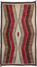 Antique Navajo area rug featuring jagged concentric lines vibrating from a small central diamond. The sharp angles and mottled tones of gray, brown, and red give the lines a dimensionality and they appear to float on the stark white field. The whole is outlined in a thin black and brown wool border.