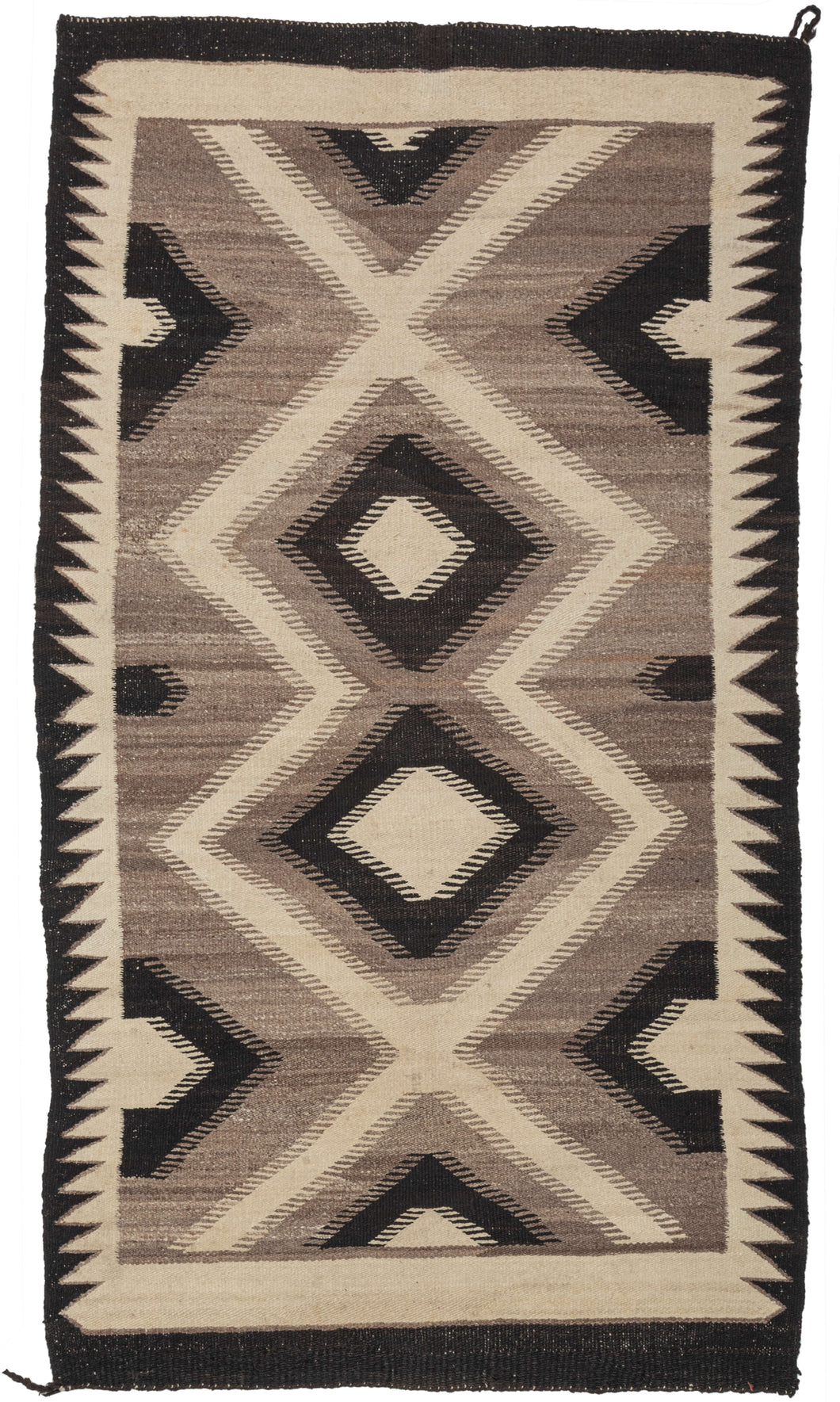 This Antique Navajo Rug features features a series of concentric diamonds in dark brown and ivory on a mottled gray background. The grey background was achieved by spinning different colors of undyed wool together. In each area where the color changes are serrated edges which give the whole composition a blurred eye-dazzling effect. Simple brown and ivory sawtooth borders frame the simple and elegant jagged diamond motif.