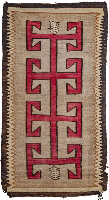 Antique Navajo small runner featuring a totemic corn stalk on a vast gray field. The gray color is created by mixing different strands of undyed wool. The whole is framed by eye-catching zigzag borders in black and white. 