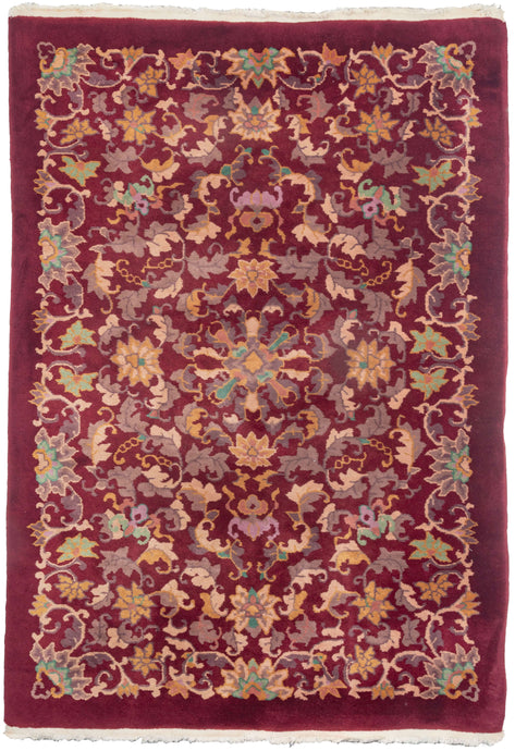 Antique deco area rug featuring a detailed naturalistic design with subtle references to auspicious symbols like lotus flowers and bats. The intricate design is rendered in an unusual combination of cream, golds, purples, and greens including both pistachio and jade on a burgundy field.