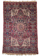 Antique Persian Lavar Kerman rug featuring a central medallion with a curvilinear floral design and scalloped cornices. The field is a rich raspberry color, nicely contrasted by the lighter pinks and creams of the cornices. The minor borders are composed of vine and leaf motifs, while the main border contains alternating blossoms in diamonds and cartouches. 
