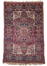 Antique Persian Lavar Kerman rug featuring a central medallion with a curvilinear floral design and scalloped cornices. The field is a rich raspberry color, nicely contrasted by the lighter pinks and creams of the cornices. The minor borders are composed of vine and leaf motifs, while the main border contains alternating blossoms in diamonds and cartouches. 