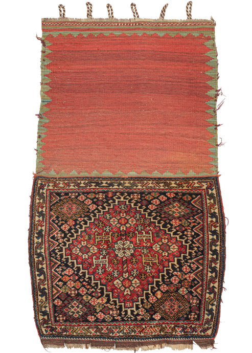 This 19th Century Kashkuli Qashqa'i Bagface features a large latch-hooked diamond medallion filled with a central talish rosette connected to four further rosettes in each direction with various smaller rosettes and protection symbols on brick red ground.  The very full central medallion appears outright spacious next to the deep navy field which surrounds it and is crowded with an abundance of rosettes that appear like flowers growing wild in a lush field.