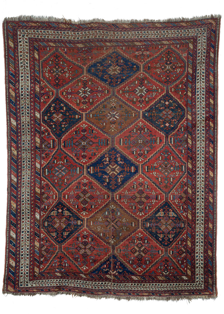 Afshar rug handwoven at the turn of the twentieth century in Southwest Iran. All over geometric pattern of lozenges filled with intricate geometric designs. Color palette of red, blues and ivory with pops of light brown and yellow. 