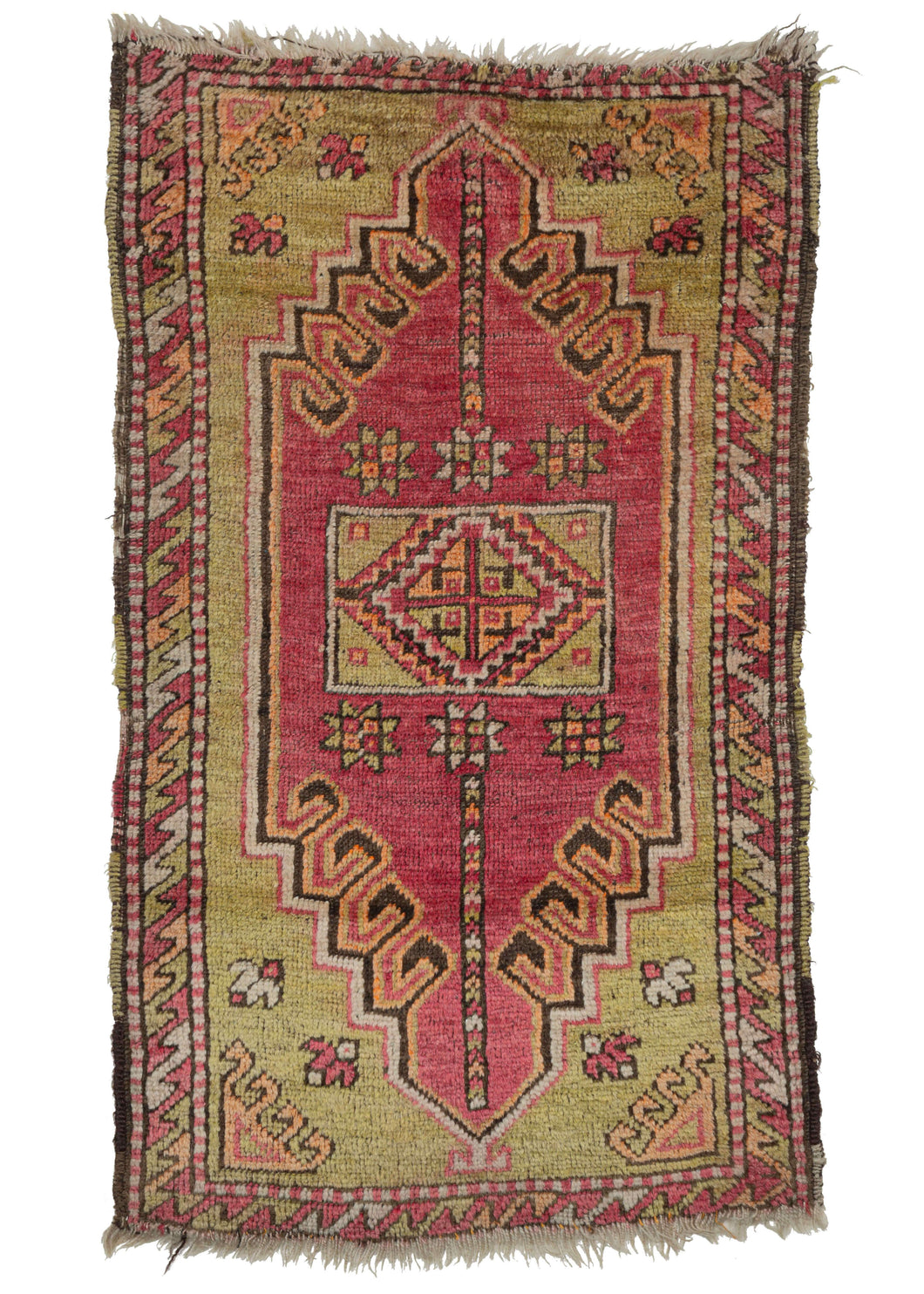 Turkish Yastik rug features a latch-hooked purplish pink field which offers a pleasing contrast with the pistachio center and cornices. Chocolate, ivory and creamsicle provide lively accents. The whole is framed by a border of tightly interlocking 