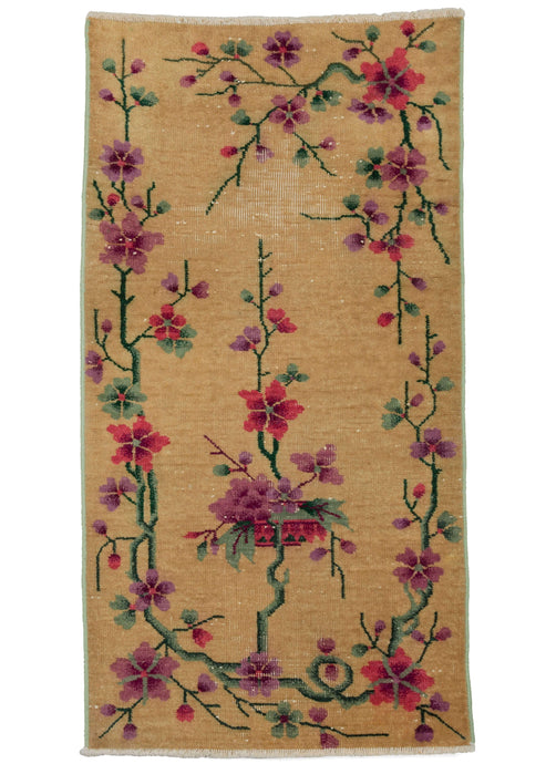 Antique yellow deco rug featuring a delicate floral design in soft purples, greens, and bright pinks, all on a yellow ground. In good condition with one worn section.  Has a low pile, and a very sturdy handle. Edges and sides have been reinforced to increase longevity.