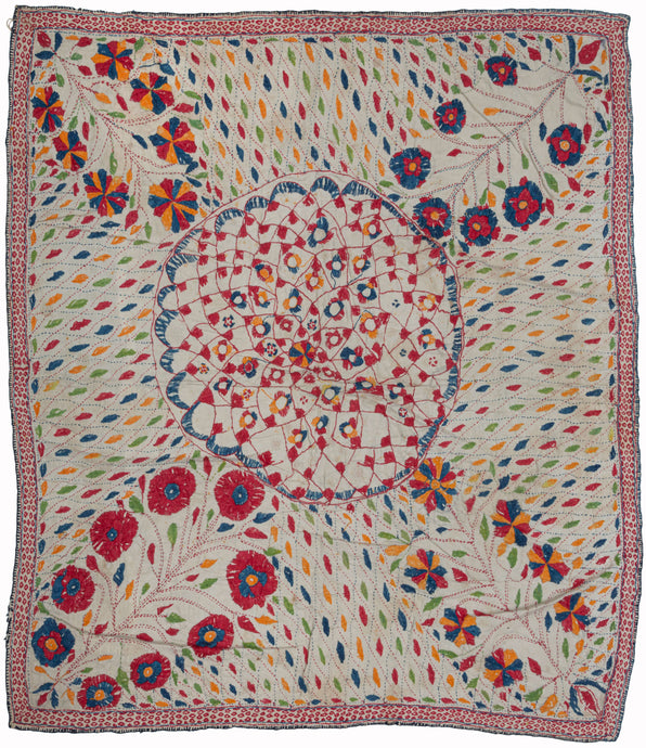 Antique Kantha featuring a detailed weblike central mandala flanked by four blossoming bouquet cornices. Each is similar yet distinctive and pokes and squishes the mandala distorting its form. The simple rendition is energized by colorful and vibrant leaf-like forms in red, blue, orange, and green cutting across the white cotton field at various angles. The whole is framed by a thin, red 