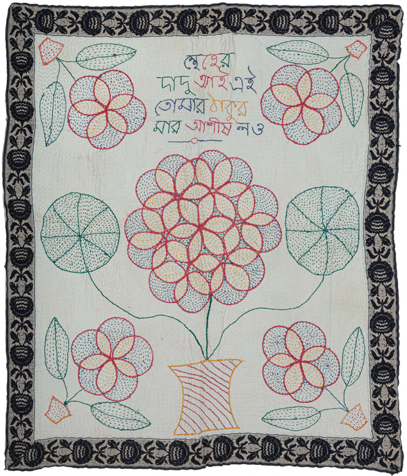 Bengali Kantha featuring a large central bouquet of flowers in a vase flanked by four smaller bouquets in vases. The leaves of the central bouquet are also interestingly rounded into pinwheel form. The outer border was taken from an old sari edge and reattached around the perimeter. The words 