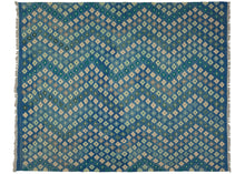 This Contemporary Maimana kilim was woven in Afghanistan during the 21st Century.  It features an allover field of rosette-like stepped diamonds in variations of greens, ivory, and gray that vibrate against the undulating jewel-toned blue ground.   In excellent condition, flat-woven with a substantial handle.