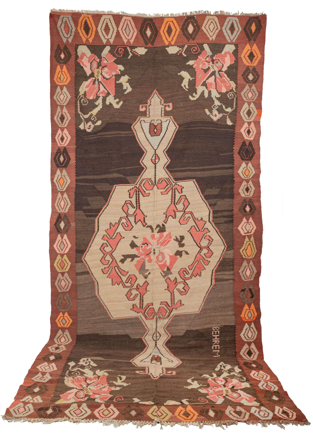 Turkish Kars Kilim featuring a scalloped central medallion with a dainty floral center surrounded by pink scrolls on camel ground. The same delicate flower featured in the medallion appears in each cornice. The field features a lovely brown which undulates wildly from light to dark brown which gives a subtle but pulsating energy. The word 
