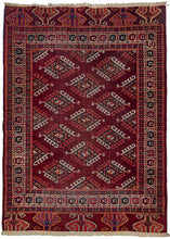 This Midcentury Yomud Turkmen Rug features an allover "dyrnak gul" latch-hooked diamond design in red, ivory, orange, green and blue on an aubergine ground. With a "curling leaf" main border and a wonderful alternating "eagle" design skirt border on the top and bottom.