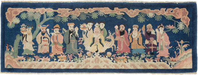 This pictorial; rug was handwoven in China during the second quarter of the 20th century.   It features a rendering of the Eight Immortals sitting atop cloudbands and amongst vegetation. These famous figures are signs of prosperity and longevity and can be represented in many different manners and often including deities or attendants as seen here. The Each immortal holds an object to identify themselves such as a flute (Han Xiangzi) or a lotus flower (He Xiangu).