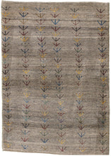 This Small Plants Grey Gabbeh features columns of vegetal-like shapes in various reds, blues, yellows, greens, and browns on a variegated gray ground. The columns are simply inconsistently drawn giving the appearance of a field of flowers swaying in the wind. The pile is densely woven, making this a plush rug.