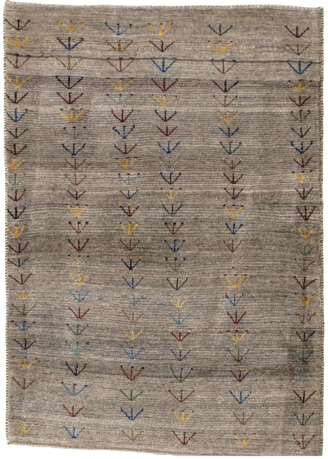 This Small Plants Grey Gabbeh features columns of vegetal-like shapes in various reds, blues, yellows, greens, and browns on a variegated gray ground. The columns are simply inconsistently drawn giving the appearance of a field of flowers swaying in the wind. The pile is densely woven, making this a plush rug.
