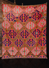 Armenian kilim handwoven during middle of the 20th century. Graphic geometric design on chocolate brown field with abrash throughout. Medallions are various shades of dark indigo to light blue. Orange details add a pop of brightness. 