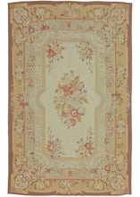 This Vintage Aubusson Style Rug was woven in classic French Aubusson style. It features a central bouquet on a cream ground and is surrounded by various classical borders. The soft and pleasing palette is rounded with different shades of soft browns, greens, yellows, and reds.