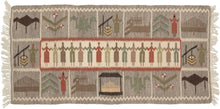 This Vintage European Kilim features a central cartouche of interlocked people in greens, browns, gray, and red on an ivory ground. They alternate between figures wearing dresses and trousers.  It is surrounded by a border of squares each depicting various people, flora, fauna, and a well amongst other things.