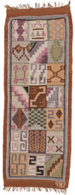 graphic peruvian kilim runner featuring a grid of diagonally repeating squares full of various abstracted shapes and symbols. It utilizes tones of soft cochineal purples and pinks, undyed browns, and greens with pops of yellow. The colors and style suggest it was woven by the talented weavers in the Ayacucho region. Very soft and lightweight, can double as a multifunctional textile or wall tapestry. 