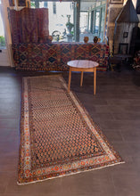 Malayer runner handwoven during second quarter of 20th century in Western Iran. Wide field with repeating multicolored boteh symbols atop dark brown field. Notes of blue, orange and yellow. 