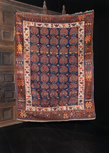 Kurdish rug handwoven during the early 20th century in Northwest Iran. Five columns of chubby paisleys on an indigo field. Ivory border encompasses and brightens the piece. Reds, blues, brown, orange and yellow. 