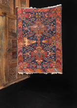 Seychur Kuba rug handwoven early 20th century in the Caucasus. Geometric cross pattern amidst a detailed floral spray. Orange, reds, and pinks atop a dark indigo ground. 
