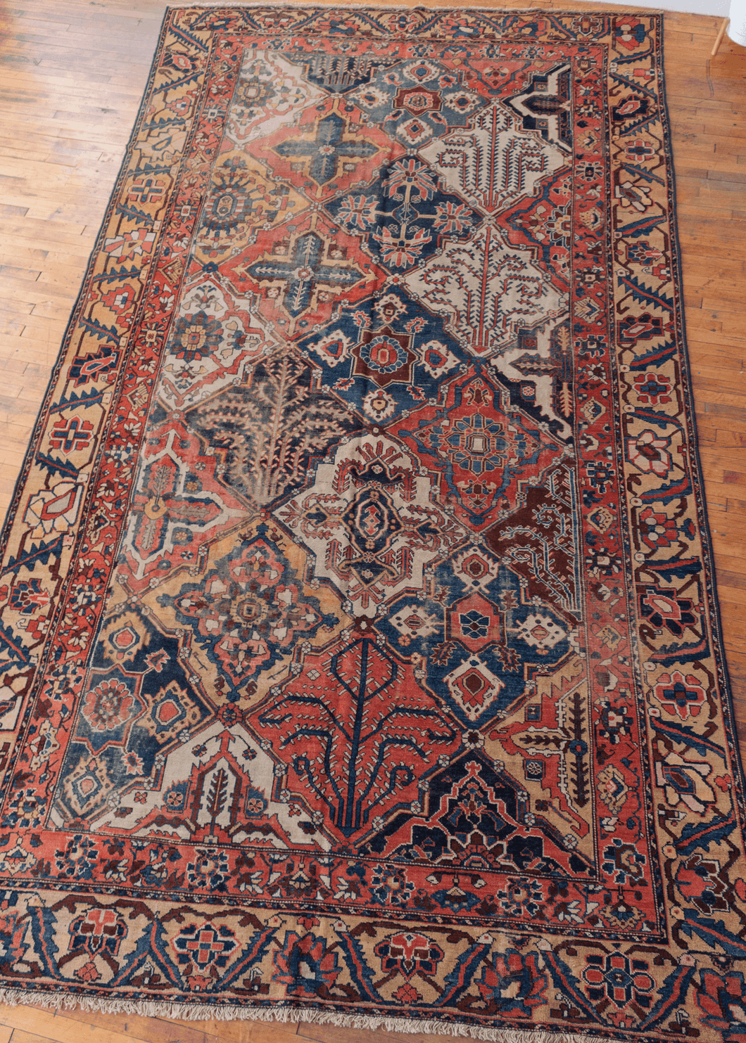 vintage bakhtiari rug with large scale lozenge pattern with garden motifs and serrated leaf and calyx border in earthy reds, yellows, blues, and browns