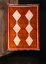 Gabbeh rug handwoven during middle of the 20th century by the Lori of Southern Iran. Simple yet bold filed with two columns of connected diamonds rendered in solid white atop a burnt orange field. 