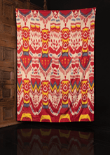 Silk ikat handmade in Uzbekistan. Silk front features a repeating abstract motif in yellow, red, blue and white atop a white field. 