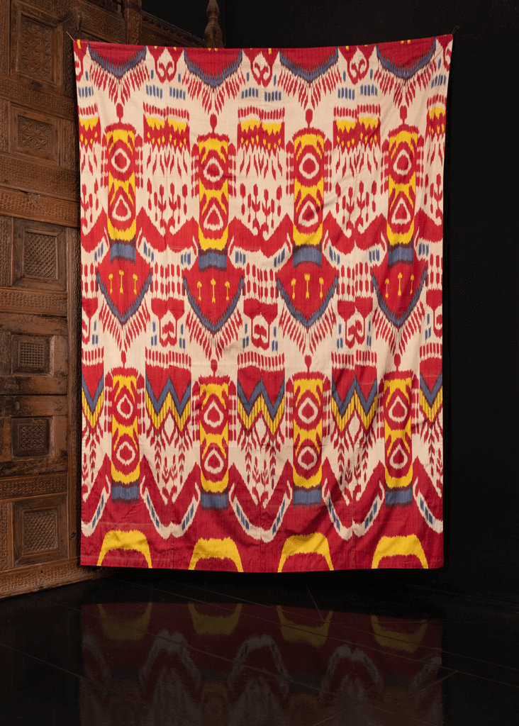 Silk ikat handmade in Uzbekistan. Silk front features a repeating abstract motif in yellow, red, blue and white atop a white field. 