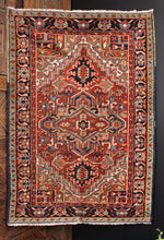 Persian Heriz rug handwoven during second quarter of 20th century. Geometric central medallion on a dark red field. Light and dark blues, golden camels and mint greens. 