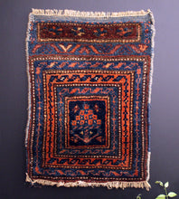 Small Kurdish rug with concentric borders that frame a bouquet of stylized flowers. Blues, oranges and reds. 