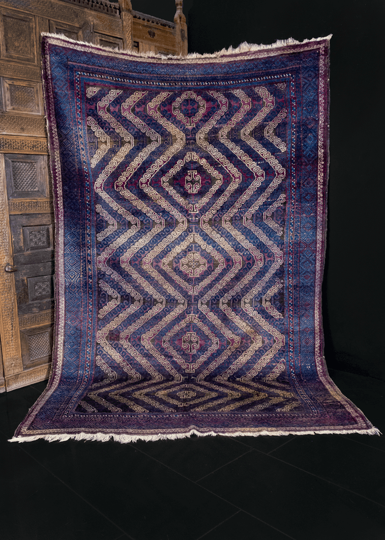 Mashwani Baluch rug handwoven in Afghanistan during second quarter of 20th century. Blue, ivory and purple field decorated with five curvilinear latch hook diamond medallions. 