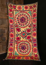 Suzani from Uzbekistan handmade during the third quarter of the 20th century. Two central medallions atop a pastel yellow ground. Flowers in bright pink and purple with green and black detailing. 