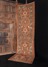 Kurdish runner handwoven in Northwest Iran during early 20th century. Large Kurdish rosettes flanked by serrated leaves in white, orange, blue, and green. Two small horses woven near the center. 