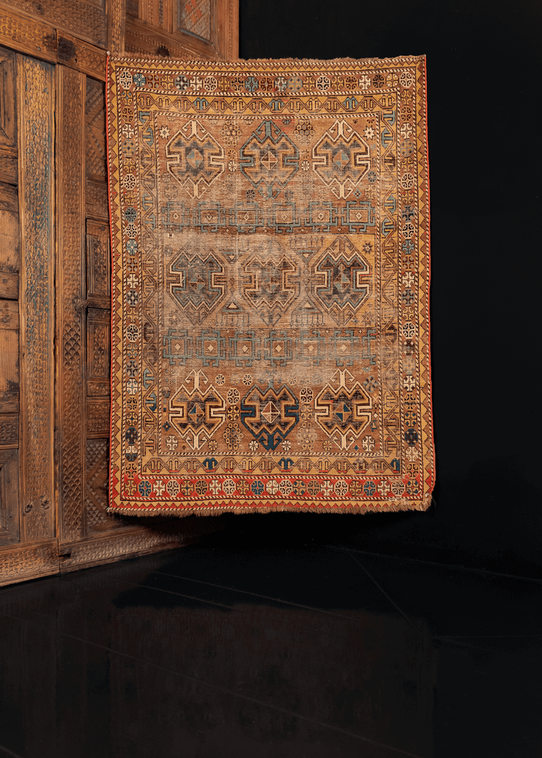 Shirvan rug handwoven in Caucasus during first quarter of 20th century. Geometric pattern of hooked squares and shield like lozenges on camel ground. Golden hues and shades of blue with red. 