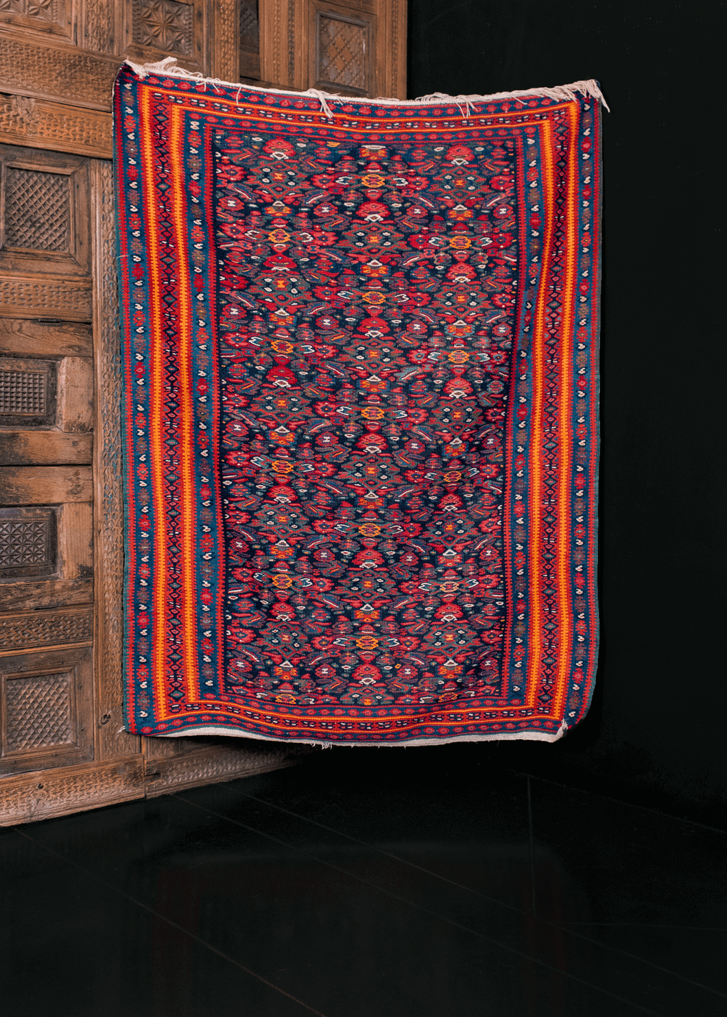 Senneh kilim in bright orange and pink on a deep blue field with allover pattern