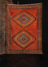 Low pile rug with a red field and multicolored concentric diamond design and floral border, in excellent condition