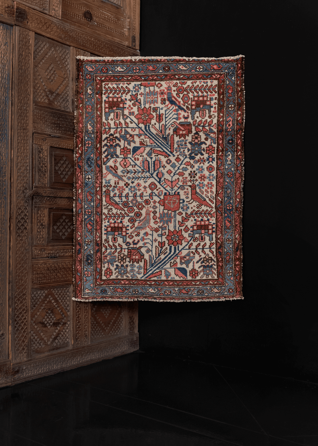 1920s Hamadan rug from West Iran in good condition with low pile and a geometric design of flowers and birds in pinks and blues on an ivory field.