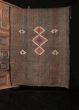 Brown kilim with goat hair and geometric shapes embroidered on top in blue orange and white