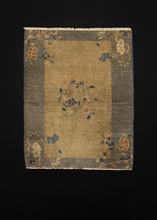 Chinese deco rug with a tan-grey field and silver grey border with floral sprays arranged in the four corners of the rug and in the center of the field. 
